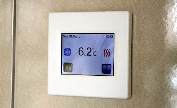Termostat s dotykovým displejem, který je nastavený na 7°C. Červené proužky vpravo znamenají, že panely topí. (Foto: Jan Potůček, Ararauna.cz)